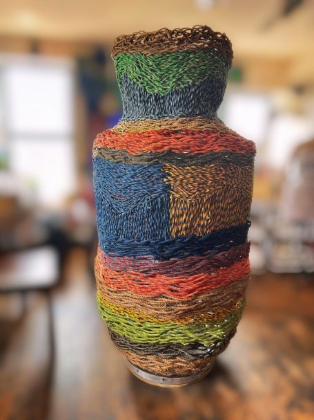 Outdoor public art, six foot multi-colored woven rope basket sculpture.