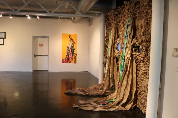 Installation view of textured wall installation with colorful fabric and video monitors embedded.