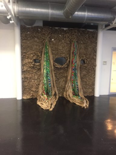 View of textured wall installation with colorful fabric and video monitors embedded.