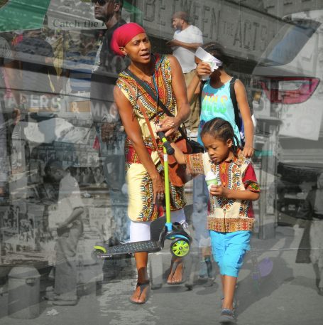 Sunday Fun Day A mother and her children walk together, carrying a scooter amidst a vibrant street scene.