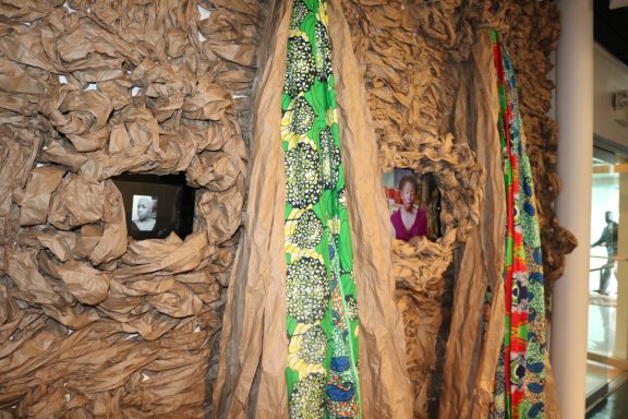 Textured wall installation with colorful fabric and two visible monitors embedded.