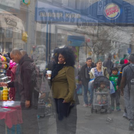 Dairy’s Choice, Shea Butter, Burger King and Things A woman in a green jacket stands in a bustling street scene with people, shops, and colorful displays.