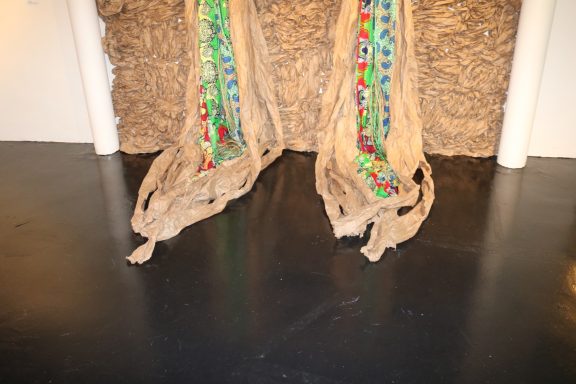 Close-up view of a textured wall installation with colorful fabric.